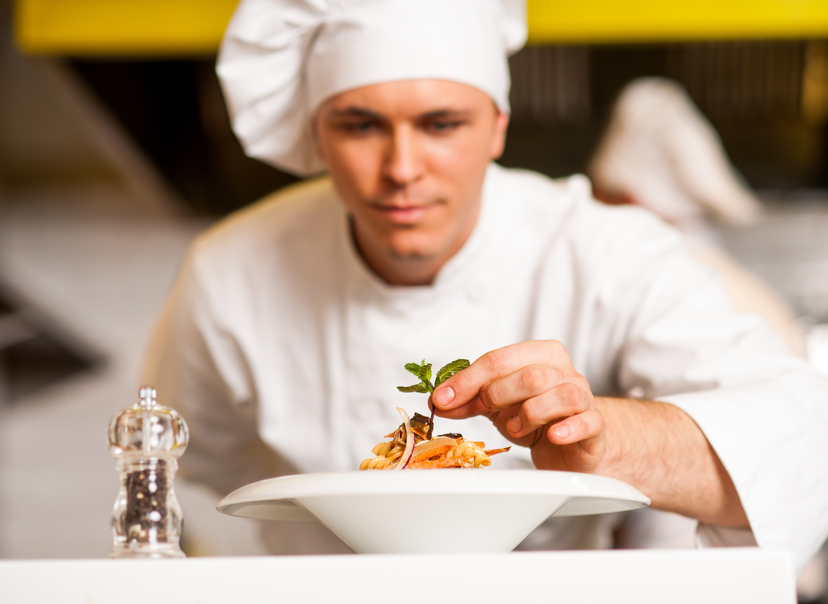 Chef decorating pasta salad with herbal leaves